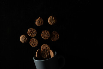 Cookies floating above a cup on dark background