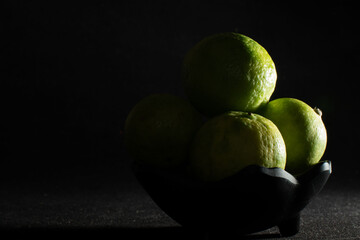 Bowl of green limes in shadow light