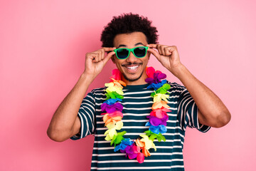 Cheerful young man in striped shirt with colorful lei sunglass against pink background