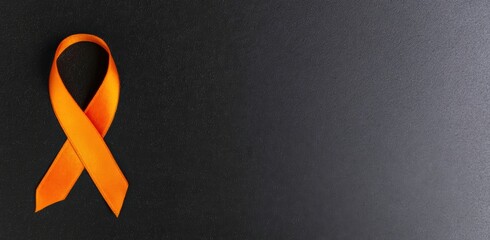 Orange ribbon laying on a dark background, symbolizing health awareness, charity support, and solidarity for various diseases