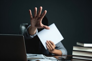 Person covering face with hand and holding a blank document, protecting privacy from surveillance or censorship