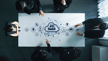 A diverse business team engages in a collaborative discussion about Software as a Service, surrounded by modern technology visuals in an innovative office environment. Trope