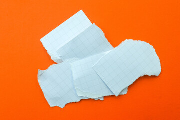 Torn pieces of white graph paper, notebook paper stacked on a vibrant orange background. Blank mockup for notes, reminders, to-do lists, and high-contrast abstract backgrounds with copy space.