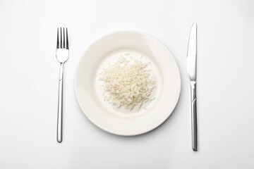 Pile of rice, plate and cutlery on white table, flat lay
