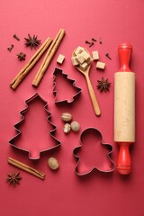 Cookie cutters and ingredients on red background, flat lay. Christmas season