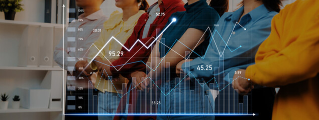 Business professionals engage with financial data in an office setting, using visual graphs to...