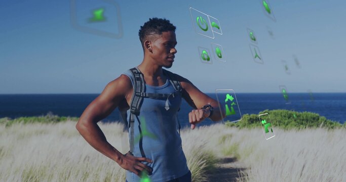Standing hiker in sleeveless top observing icons on coastal dune trail with backpack and smartwatch
