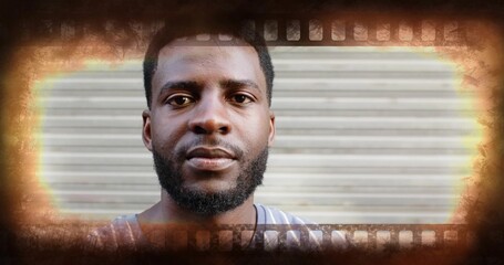 Posing adult male in sleeveless shirt on street, with metal shutter and vintage filmstrip frame