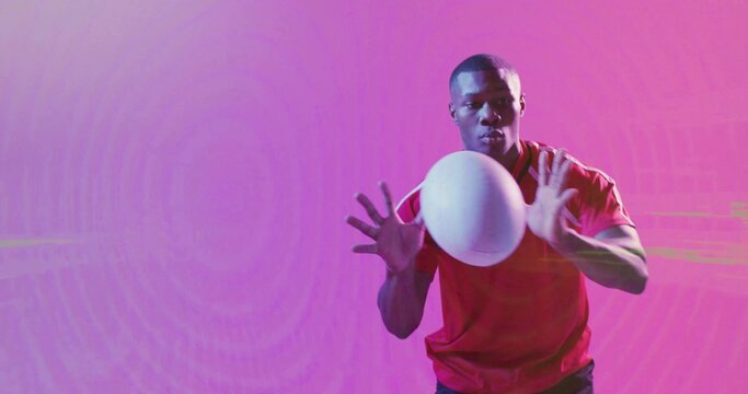 Reaching male athlete wearing red t-shirt catching white sports ball in gradient studio, copy space