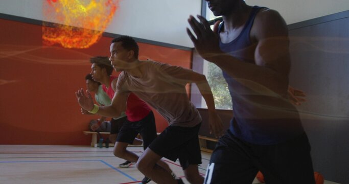 Leaning forward four male athletes in sportswear launching sprint drills at gym, with basketball