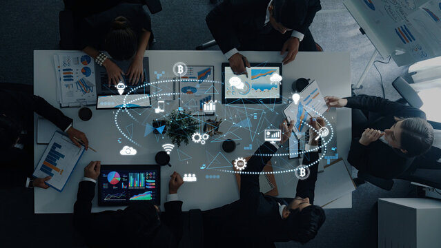A diverse group of business professionals collaborates in a modern office, analyzing data displayed on digital devices to create strategic insights and foster innovation. Trope - Powered by Adobe