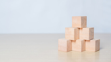 Hand arranging wooden blocks stacking as a pyramid staircase on white background. Success, growth,...