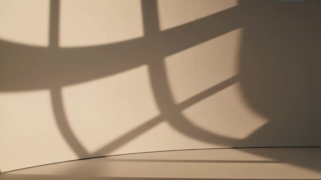Abstract composition of geometric shadow shapes from window panes falling on a curved, light-colored wall. Sunlight creates a serene atmosphere in a modern, minimalist space.