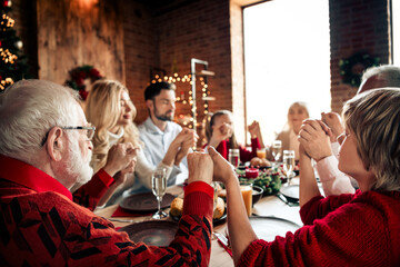Family gathering around a festive Christmas dinner at a cozy home with decorations and lights celebrating together during winter eve
