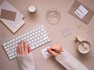 A feminine workspace flat lay top view on a calm beige background, featuring a close-up of a...