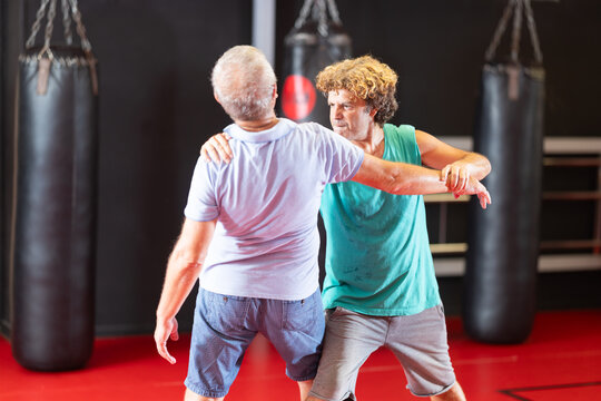 Purposeful male pupil clash with training manager during self-defense lesson, repulse charge, intensity of practice