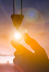 Hand Holding Crane Hook Silhouette Against Sunset Light, Industry Safety Concept