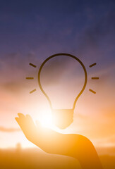 Creative idea and inspiration concept with light bulb in hand at sunrise