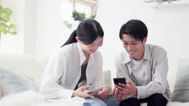 笑顔でスマホを見るアジア人カップル