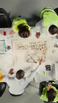 Vertical Video Top down view zoom in of real estate professionals using architectural software to refine housing layouts and 3D models. Development team collaborates on zoning regulations and
