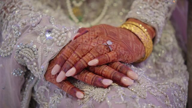 Traditional henna painted bridal hand with golden bangles and engagement ring. 