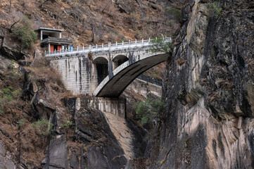 An old bridge opposite the landscape of Tiger Leaping Gorge in Yunnan province of China. Scenic spot where a tiger is said to have leaped across the river, thus giving the gorge its name.