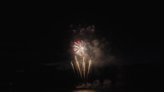Colorful fireworks exploding above the lake. Slow motion