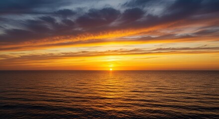 Naklejka premium Dramatic golden hour colors paint the vast sky above the calm ocean horizon as the sun dips below the water line creating a stunning view ,orange ,twilight ,red