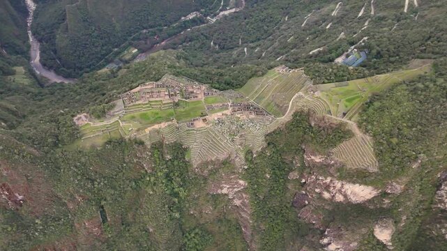 Aerial shot starts with a downward-facing close-up of urban section, flies lower elegantly panning camera upward to reveal impressive, walls of ancient Inca structures, focusing on House of Factories