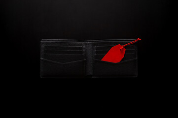 Black Friday concept with an open black wallet holds a red price tag on a dark background.