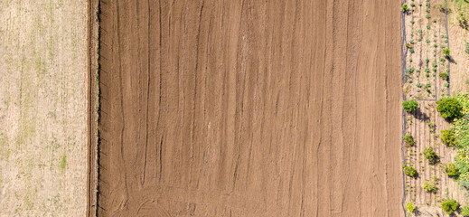 A top down aerial shot of a freshly plowed field next to a harvested field creating a beautiful natural background of lines and textures © bugrakaanersoy