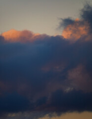 A moody and abstract vertical shot of dark storm clouds with hints of pink and orange from a sunset a dramatic and powerful sky