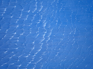 A mesmerizing abstract texture of wind swept snow creating a beautiful and rhythmic pattern of blue and white a perfect winter background