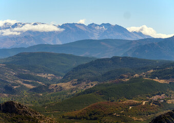 A beautiful and vast mountain landscape with a green valley and distant peaks partially covered by clouds a perfect travel destination