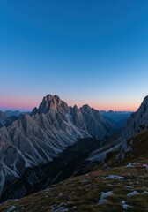 Fototapeta premium Serene mountain landscape at dusk, showcasing rugged peaks, deep valleys, and the transition from warm sunset colors to cool, peaceful blue twilight ,summit ,scenic ,blue