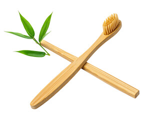 Two crossed bamboo toothbrushes, bristles up, are accented by bright green leafy sprig against a solid black backdrop