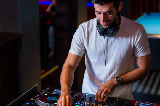 A professional DJ mixes a live set on a controller in a dark nightclub or bar A concept for electronic music entertainment and nightlife culture