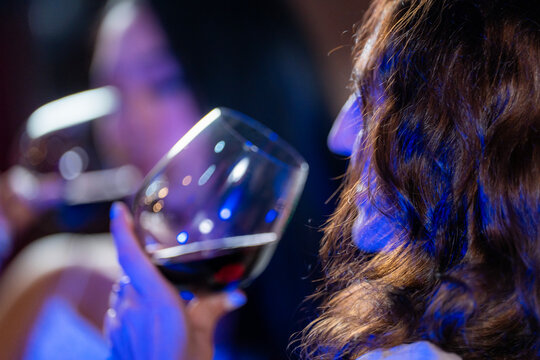 An elegant young Asian woman in a glamorous sequin dress smiles at a party holding a glass of red wine A concept for luxury lifestyle and formal celebrations