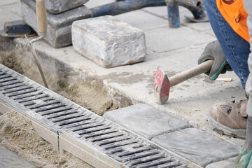 Worker laying pavement stones in city street