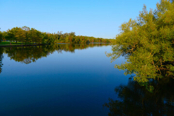 Fototapeta premium Calm blue lake reflects trees
