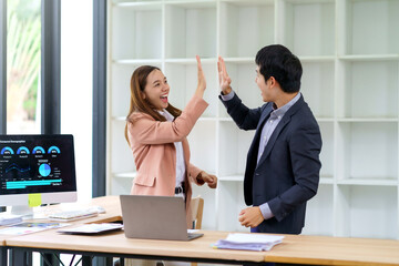 Business partners performing a high five, celebrating a successful achievement in a modern office workplace