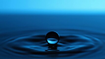 Close-up of a single water droplet falling into calm blue water, creating ripples - Powered by Adobe