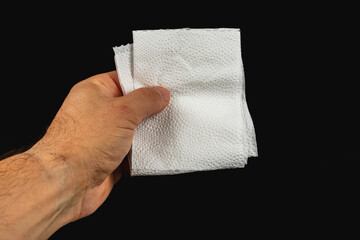 Hand holding clean paper towels against plain black background