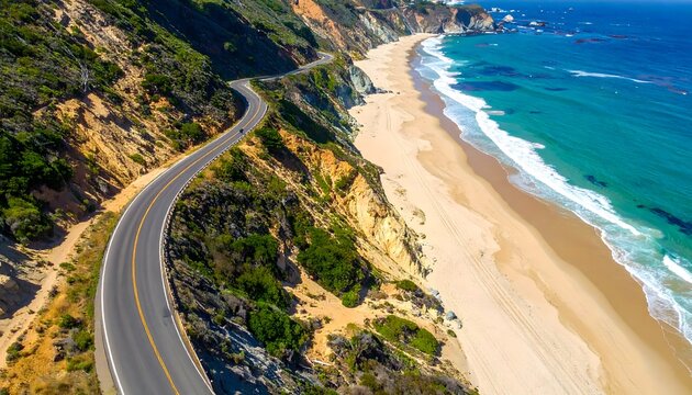 Aerial view of a scenic coastal road winding along a dramatic cliffside with a beautiful sandy beach and turquoise ocean