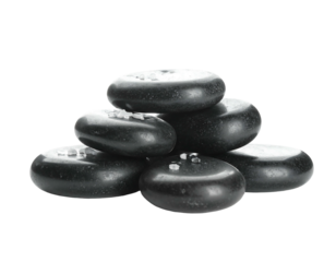 Smooth black stones stacked into a pyramid, adorned with white specks on top, set against a solid black background
