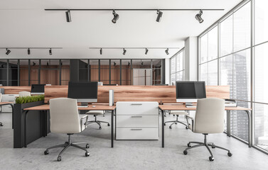 Open office interior with wooden desks, rolling chairs, desktop computers, and natural light from glass walls in city tower. Concept of workspace. 3D Rendering