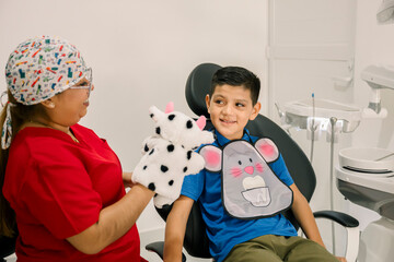 Pediatric dentist entertaining young boy with puppet during checkup