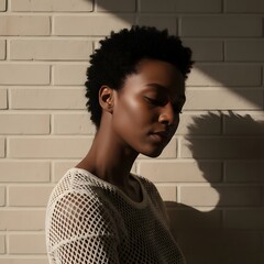 Artistic portrait of a serene young woman standing by a brick wall in soft sunlight, with gentle shadows highlighting her natural beauty, elegance, and introspective mood in minimal warm tones