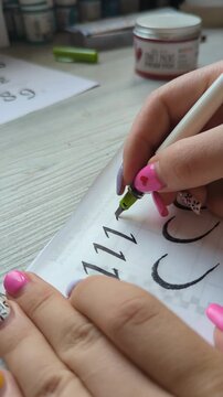 Elegant calligraphy practice, female artist hand using pen to draw smooth, decorative lines. Focus on handwriting art, concentration, and design aesthetics. Lettring process close up.
