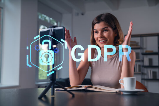 Happy woman is making video blog using smartphone on a tripod explaining with hands at office workplace. Concept of online stream, business education, conference call. Information security hologram